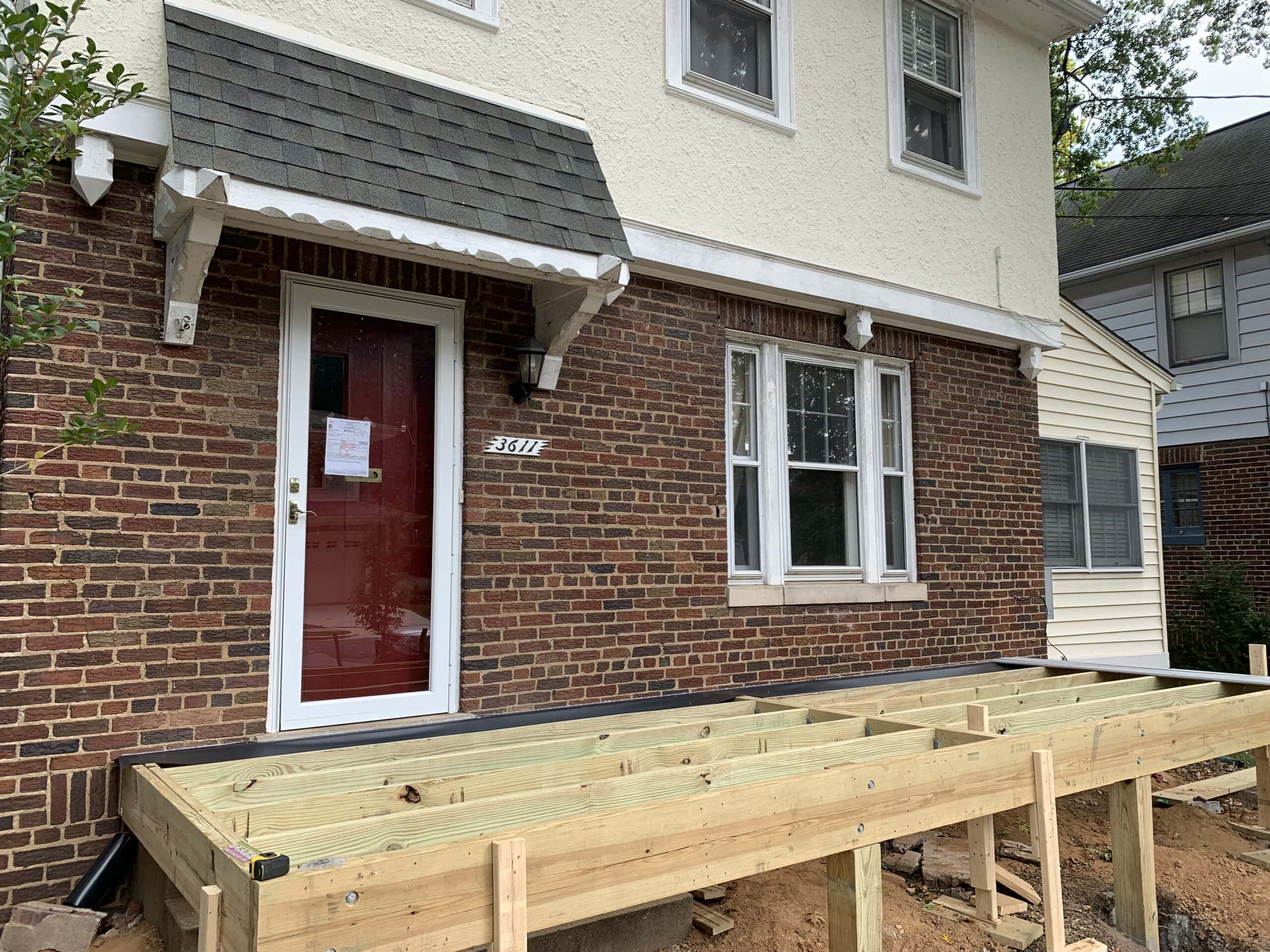 A house with a porch and a deck being built.
