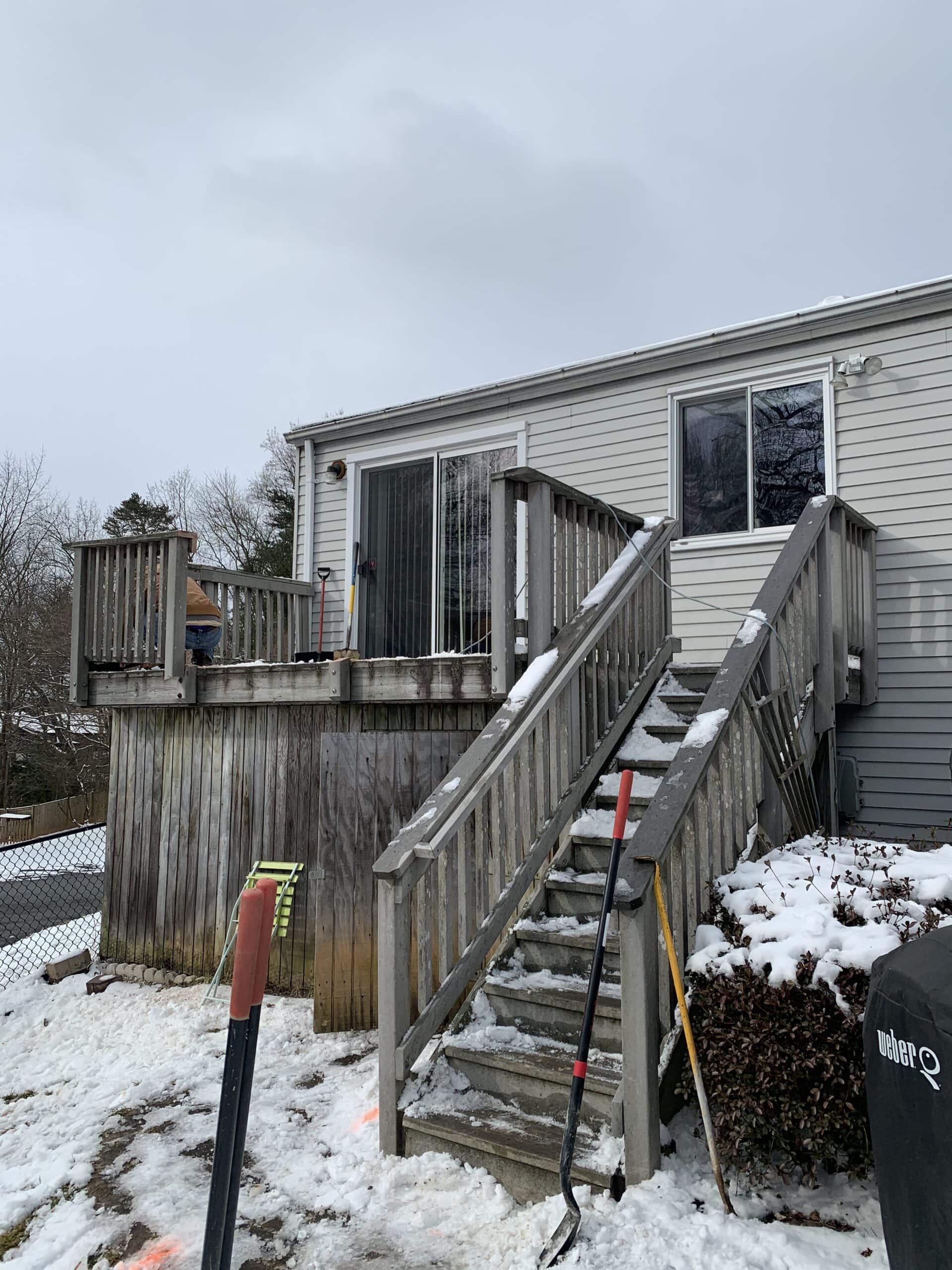 A house with a snow covered deck and stairs.