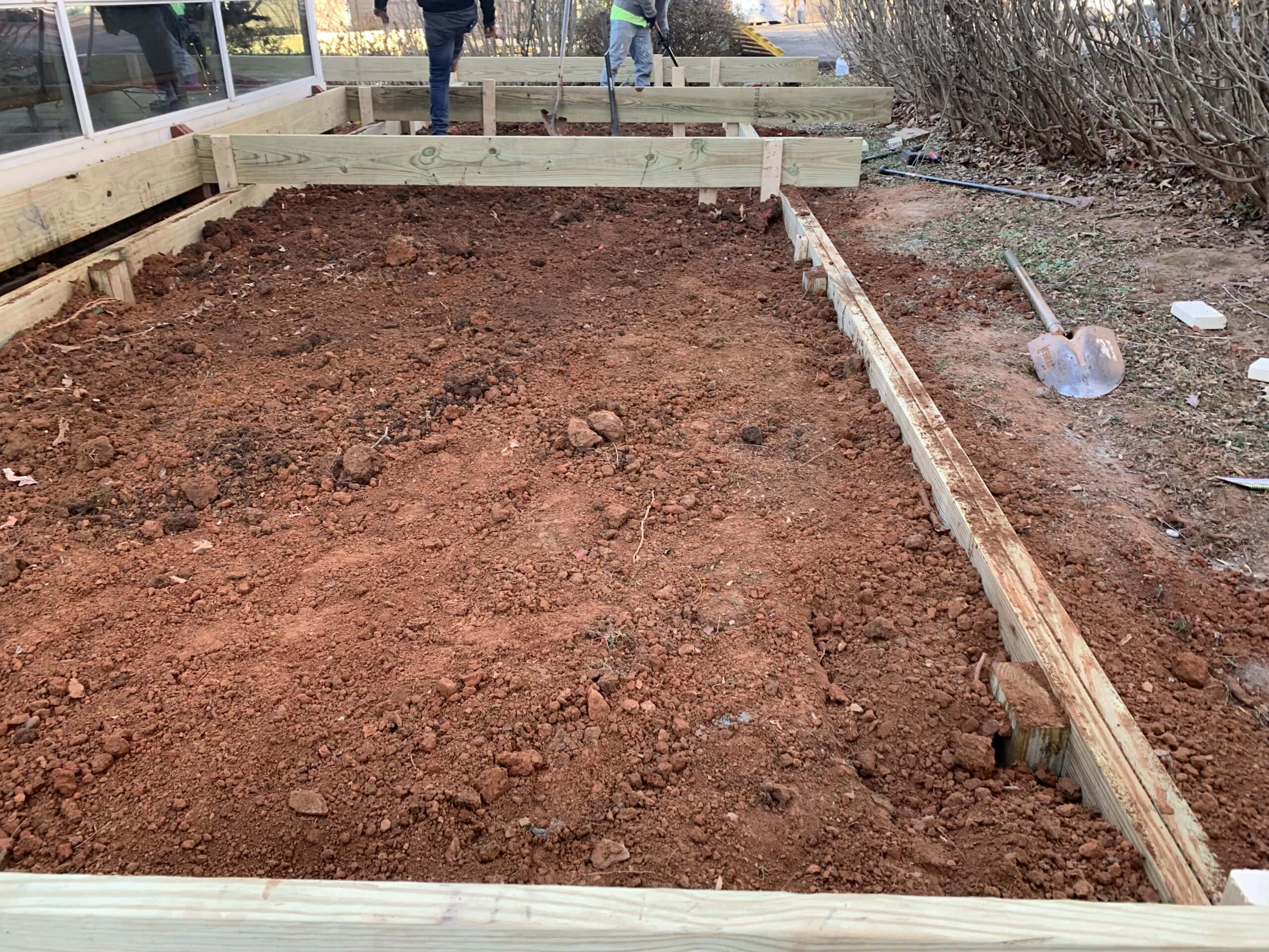 A man is working on a wooden deck with dirt.