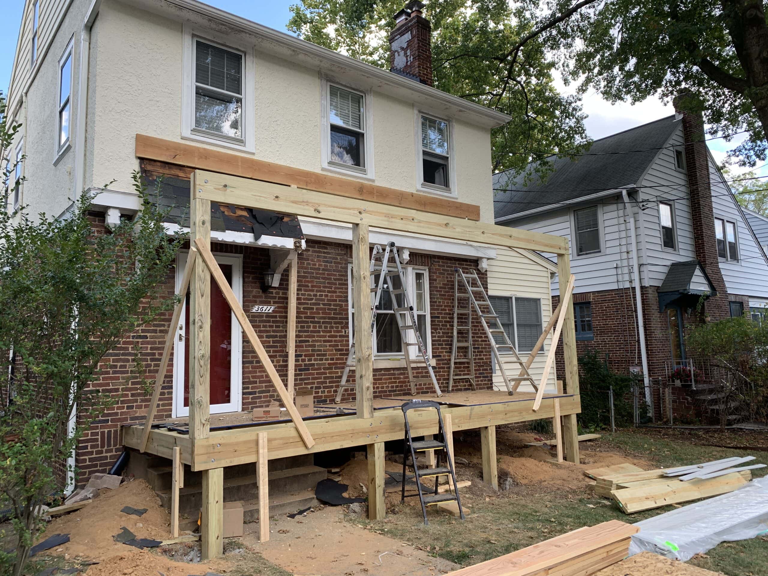 Initial framing stage of new front porch, with wood beams and supports in place.