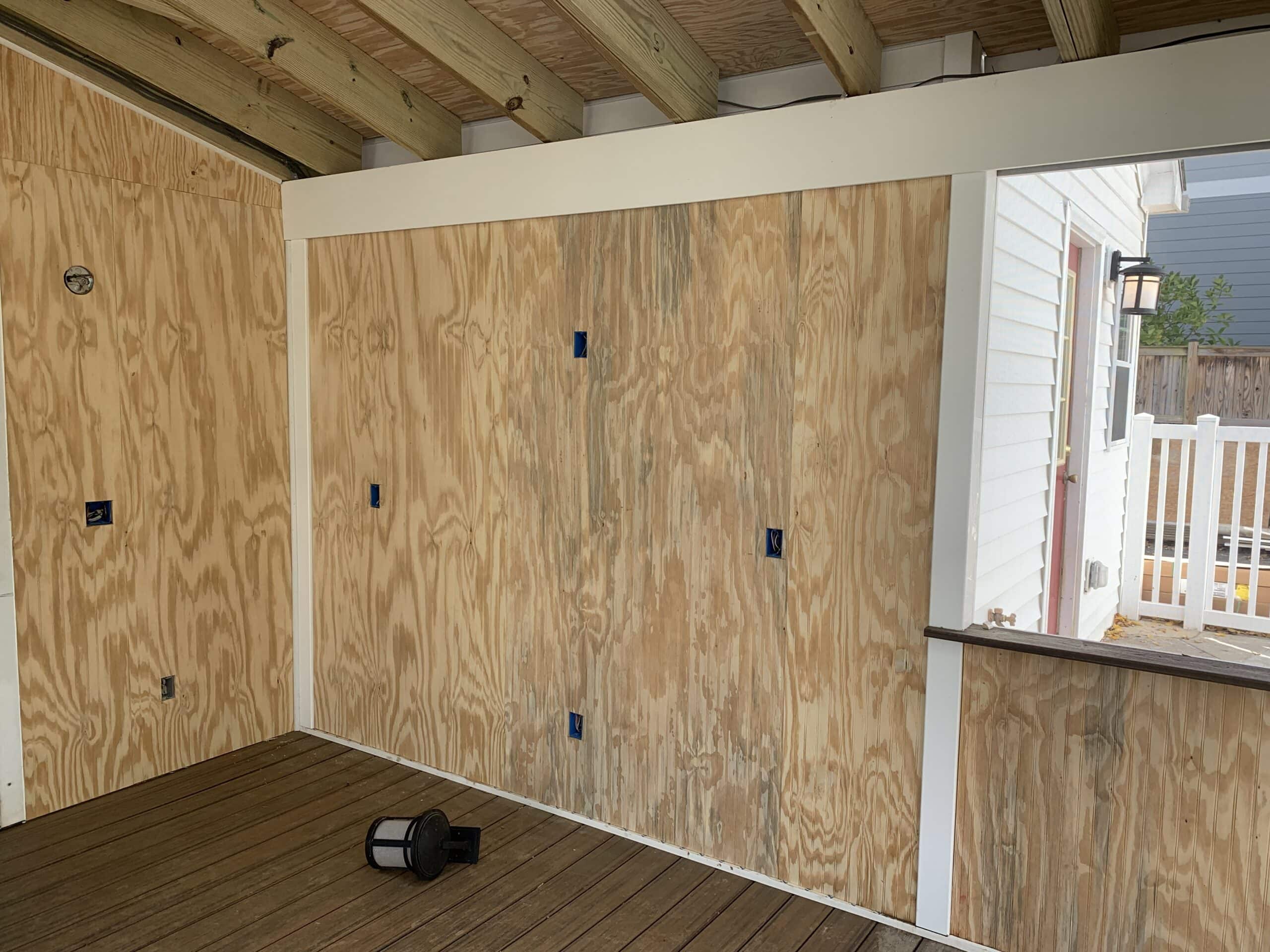 A wooden deck with plywood panels and a door.