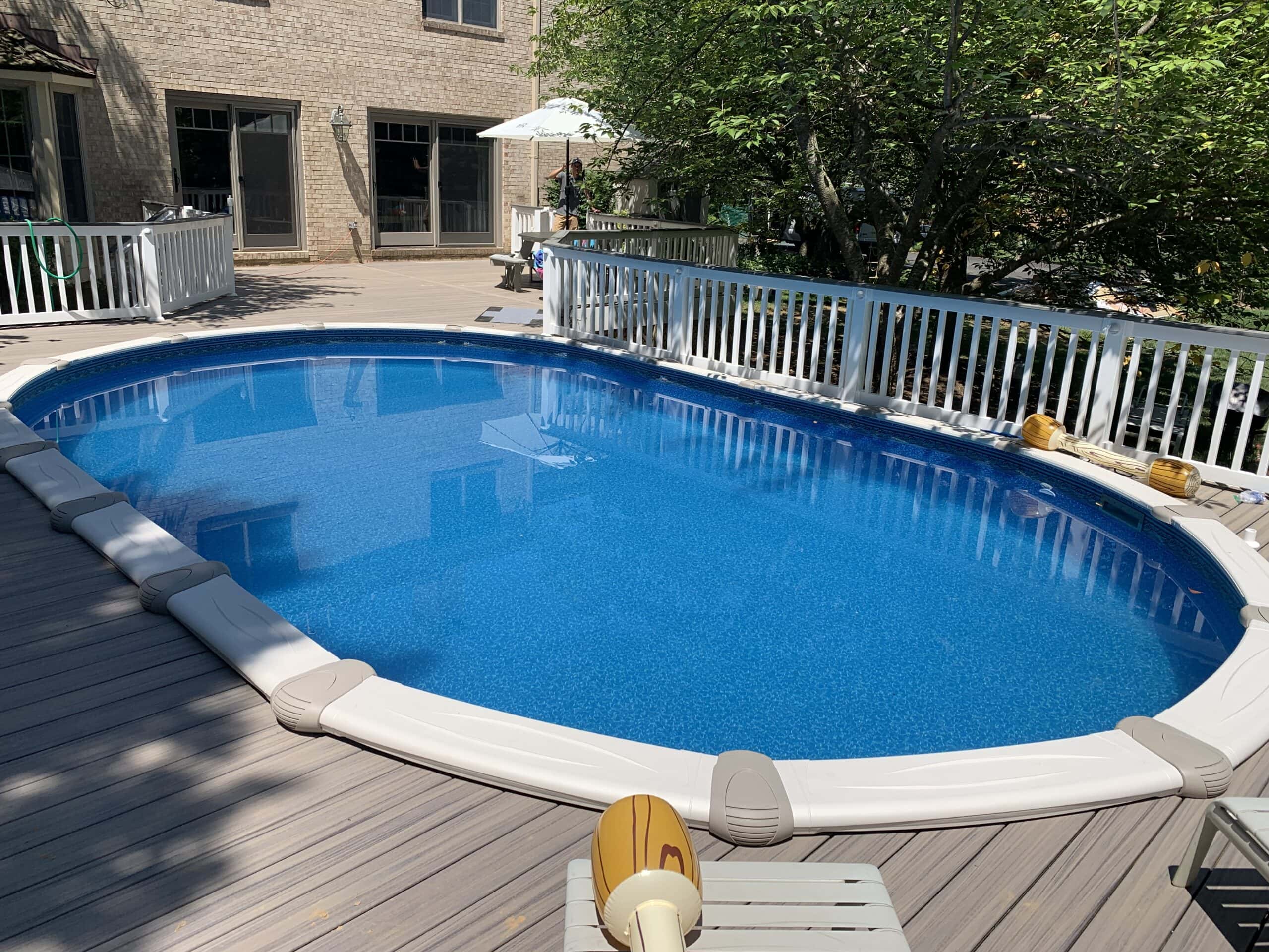Completed curved Trex deck wrapping an above-ground pool with clean railings and blue water