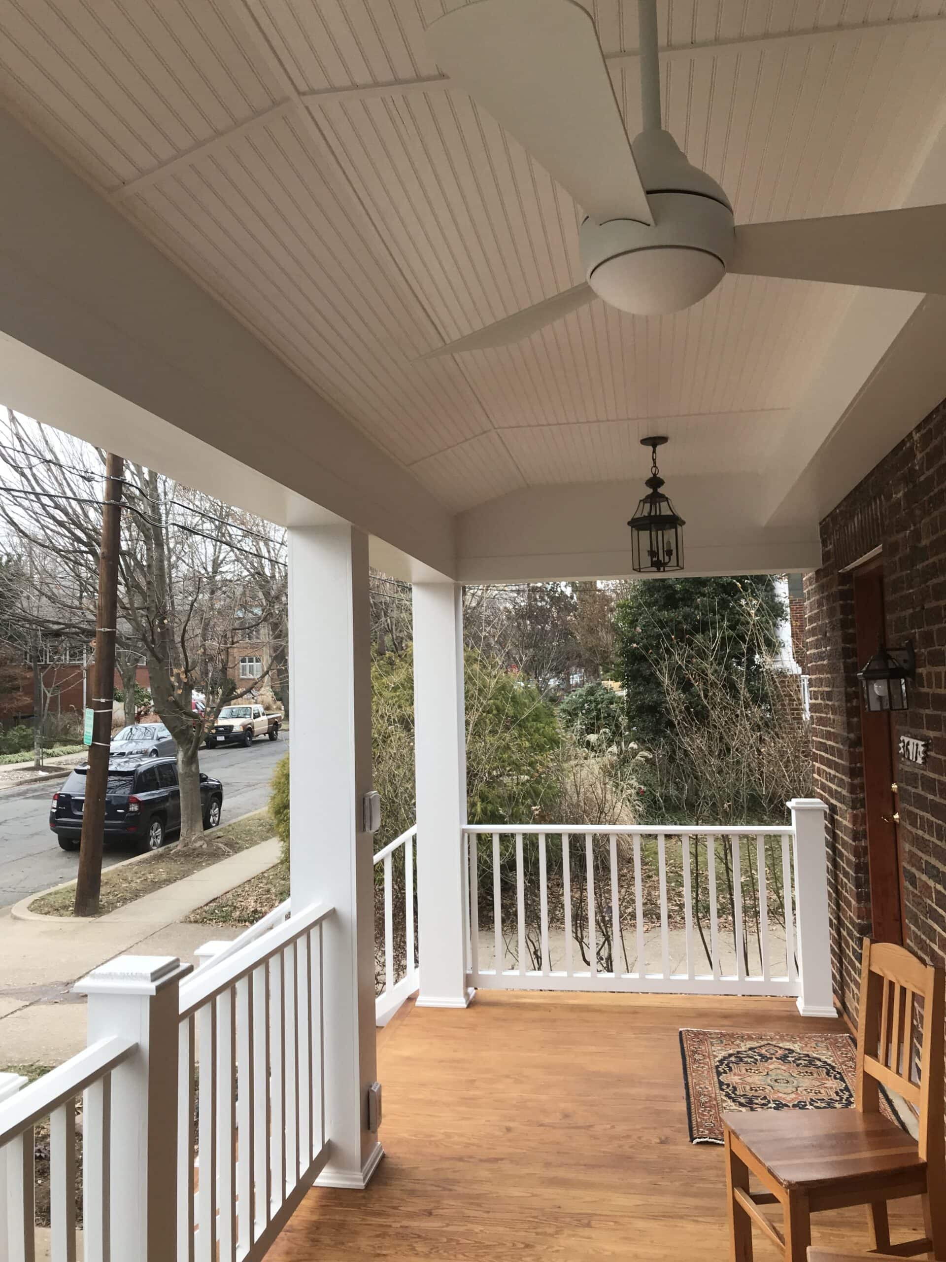 A porch with a ceiling fan and a bench.