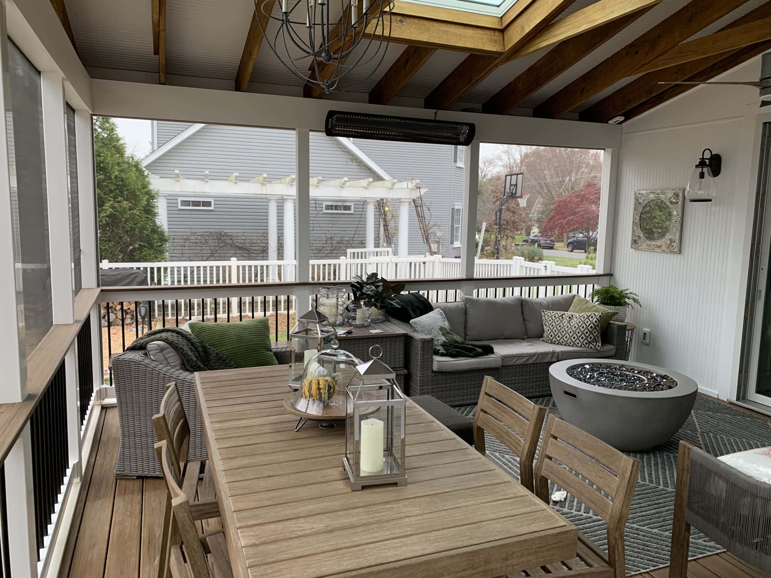 A screened porch with furniture and a fire pit.