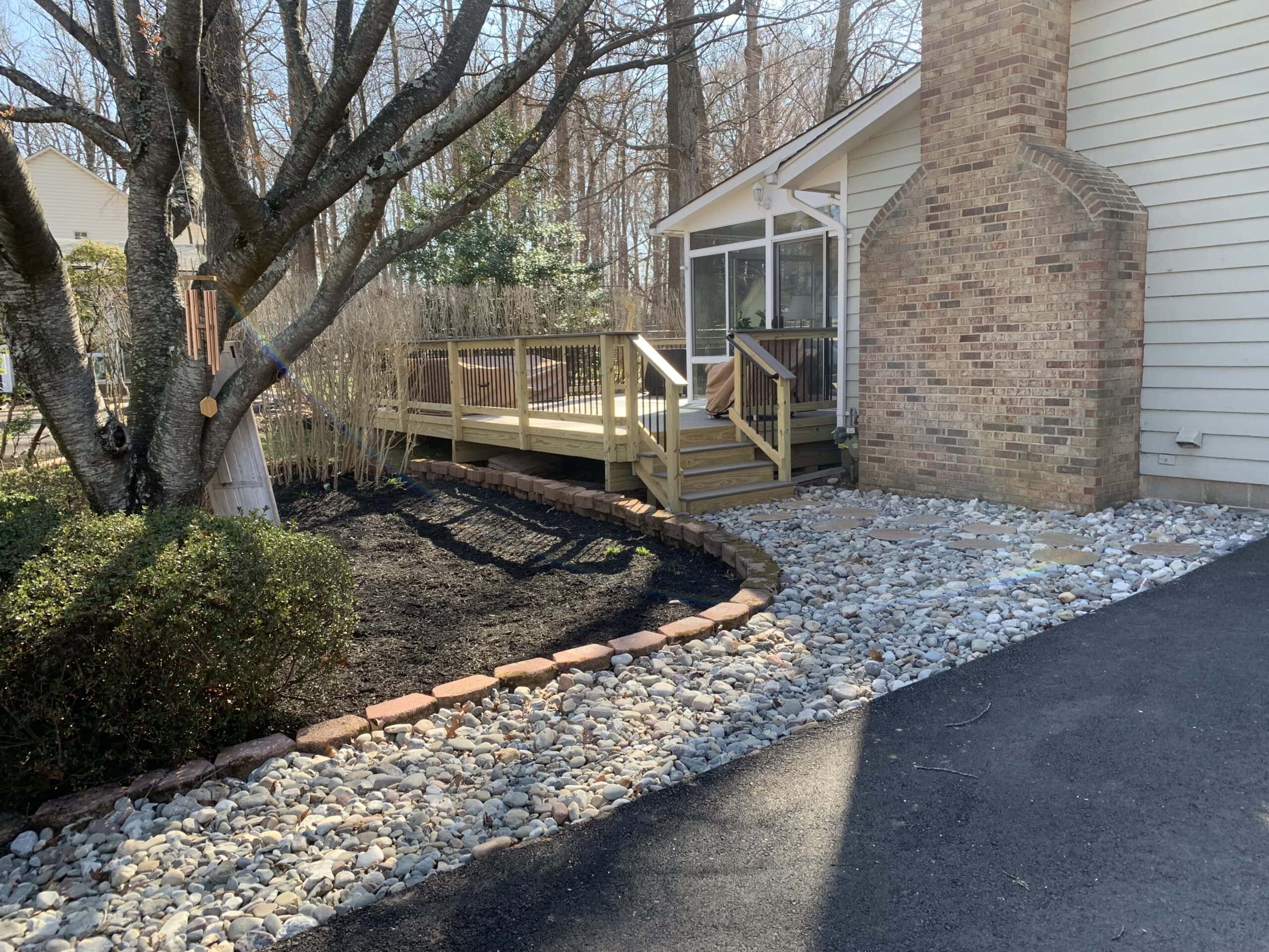 A backyard with a deck and a tree.