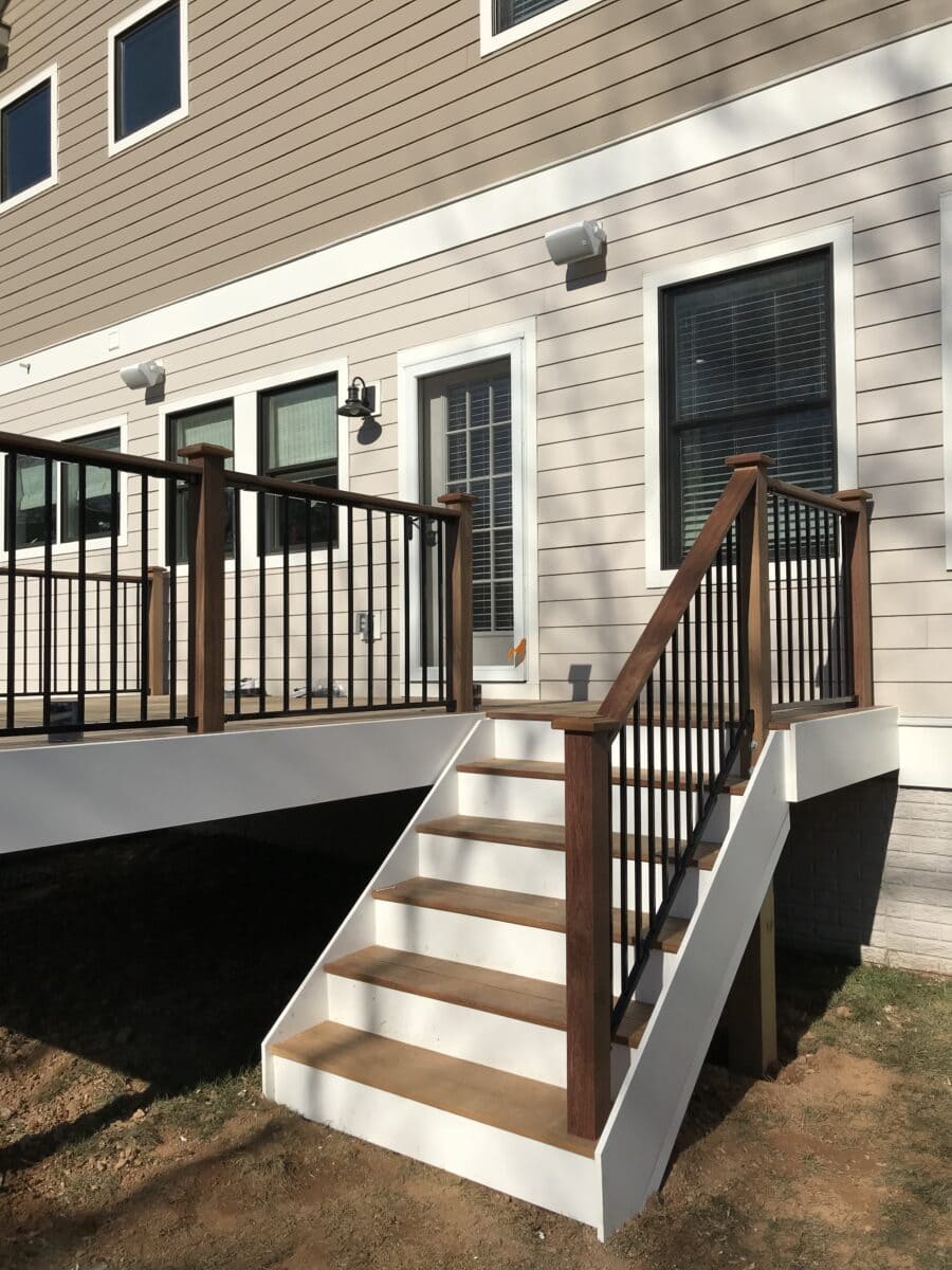 Backyard deck with white stairs and black metal railings