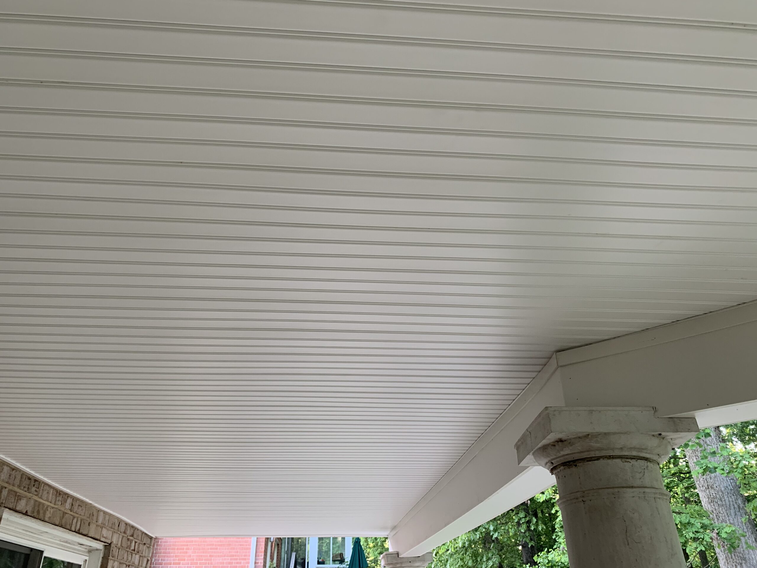 A white covered porch with columns and a table.