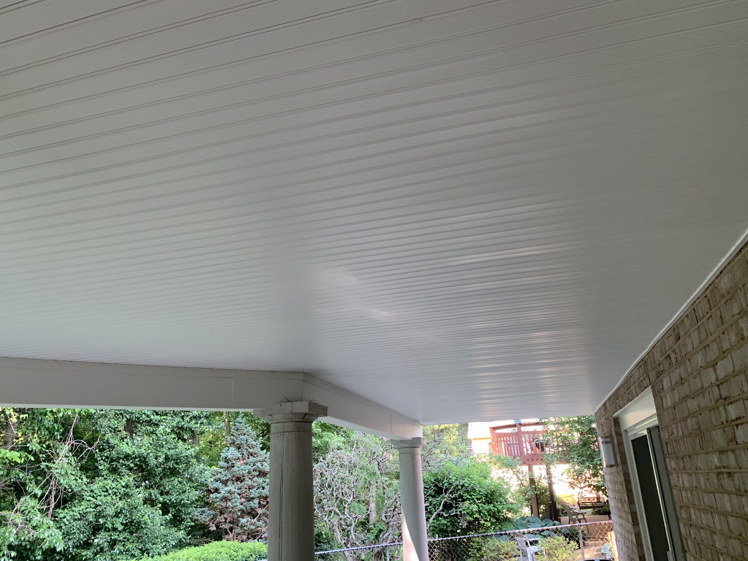 A white covered porch with columns and a table.
