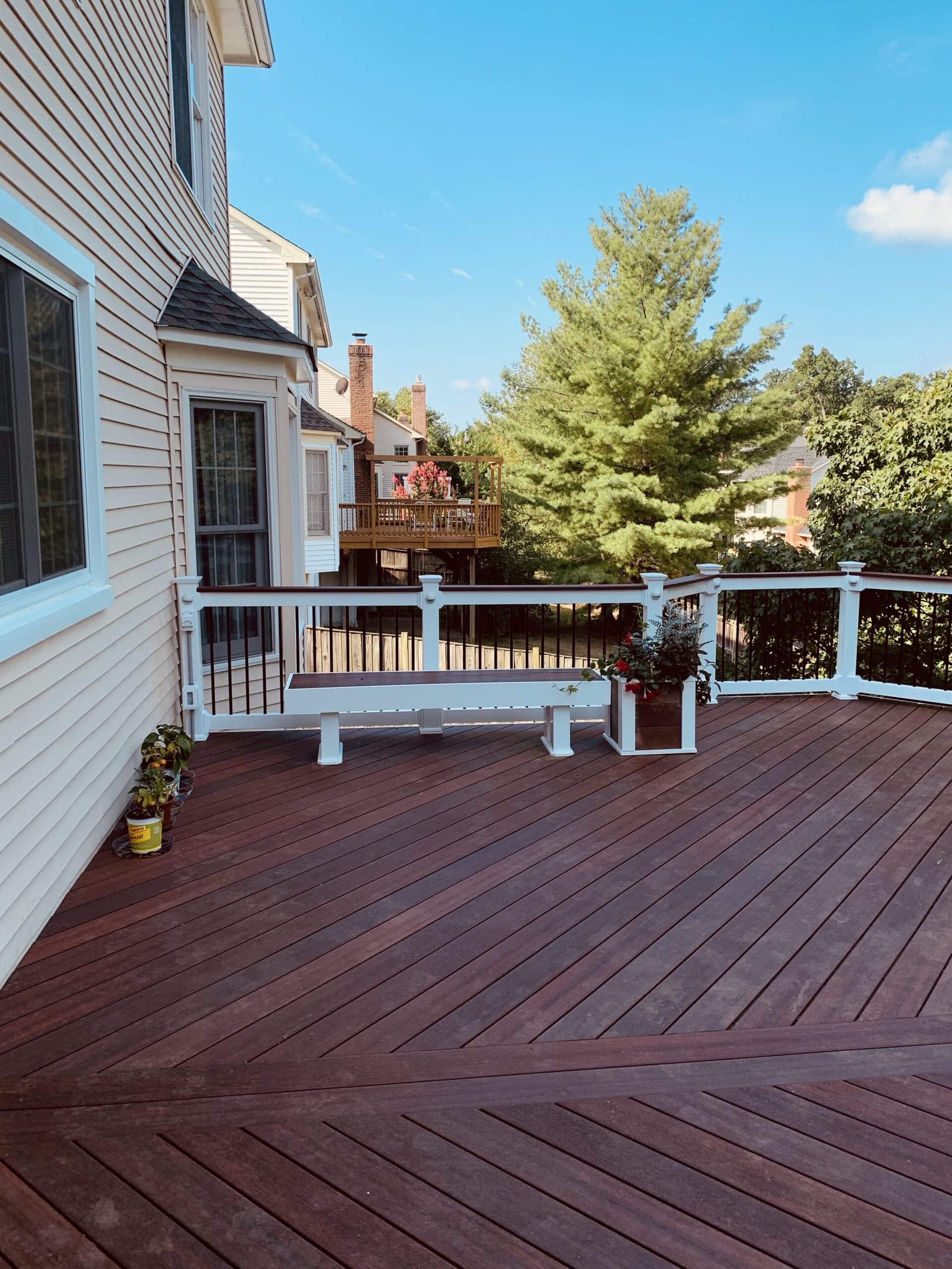 A wooden deck with a bench and a white fence.