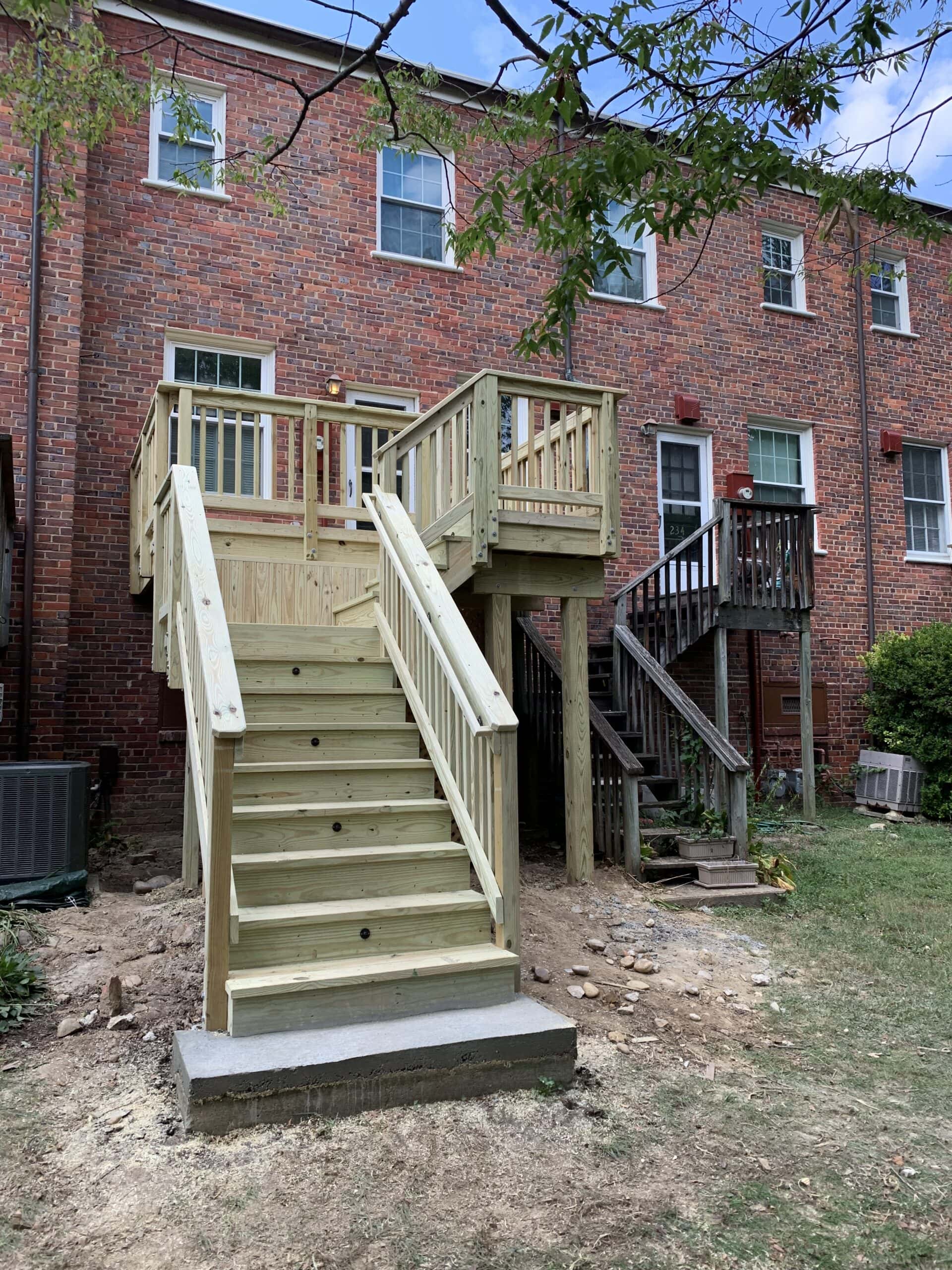 A wooden staircase leading to a deck in front of a house.