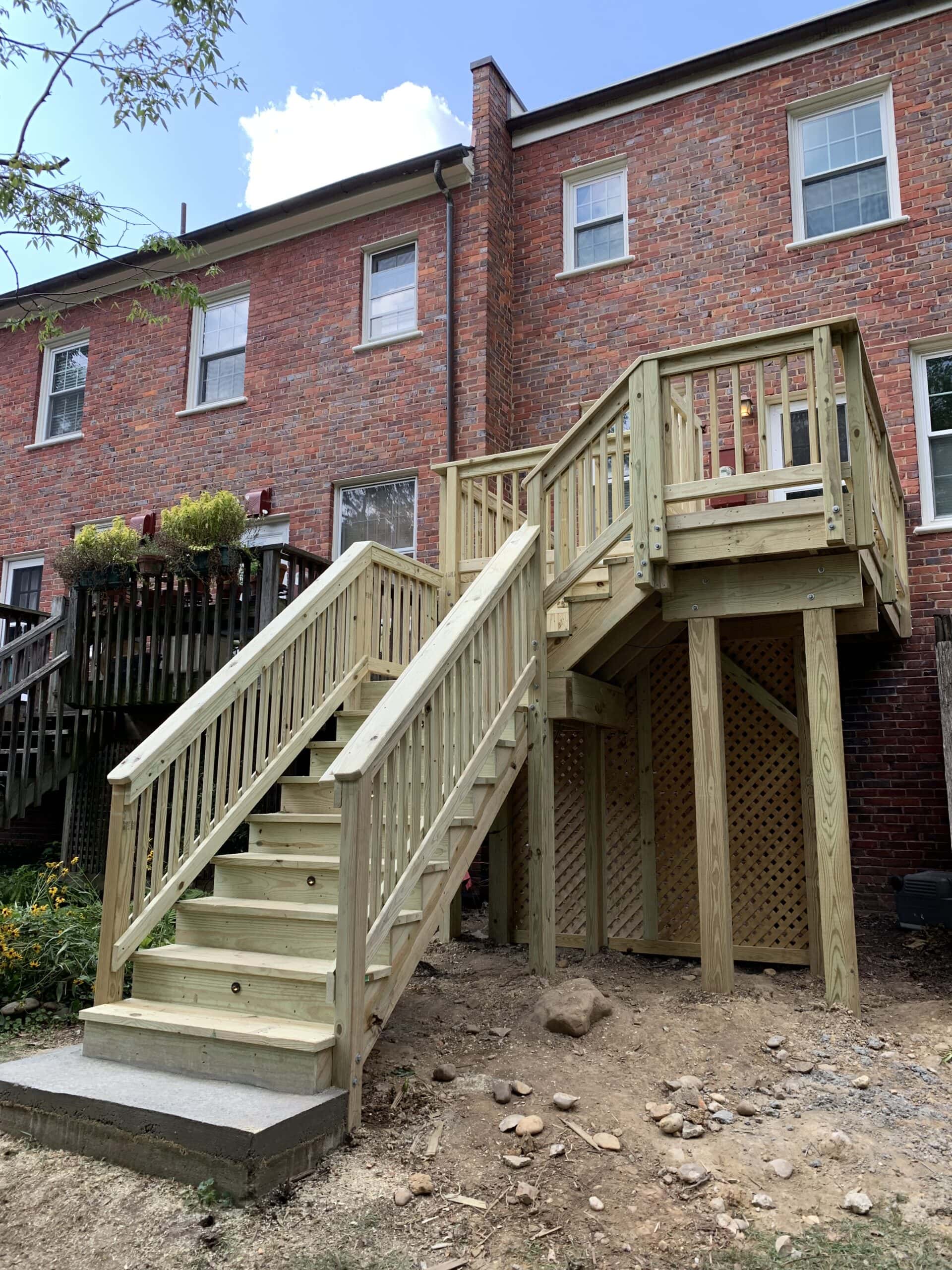 A wooden staircase leading to a deck in front of a house.