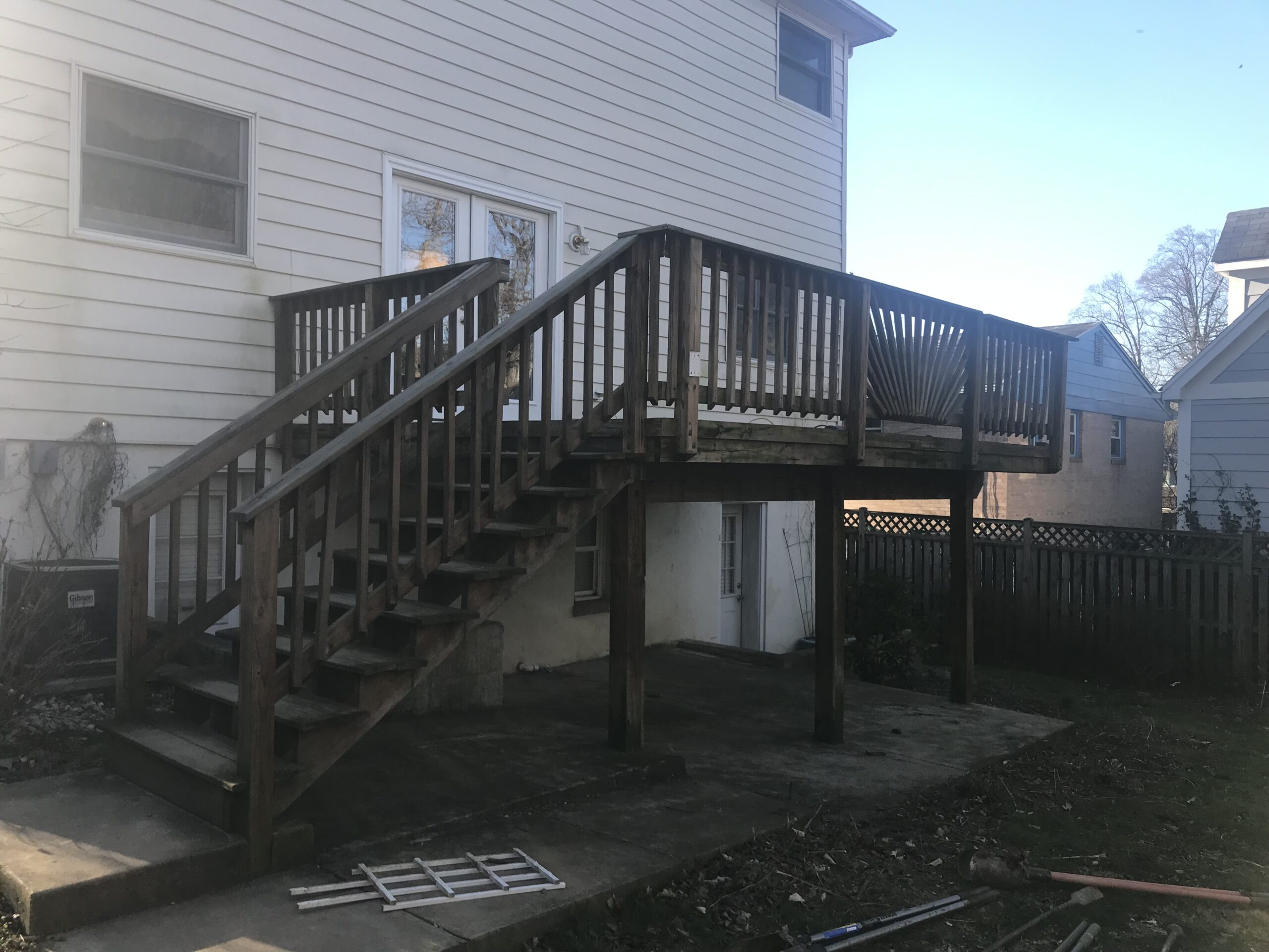 A deck with stairs and a porch in front of a house.