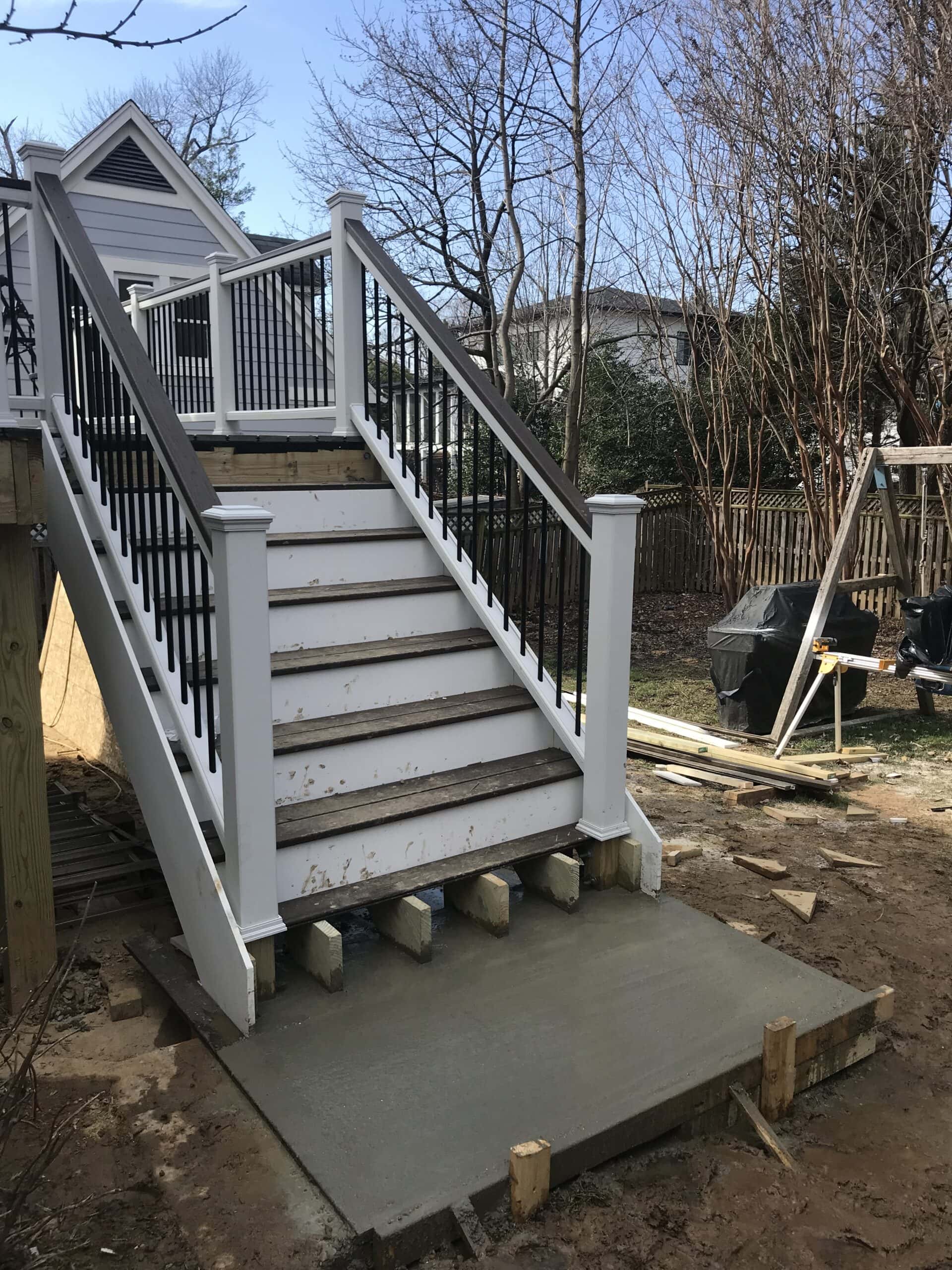Completed outdoor staircase with white railings and black balusters leading to a finished elevated deck