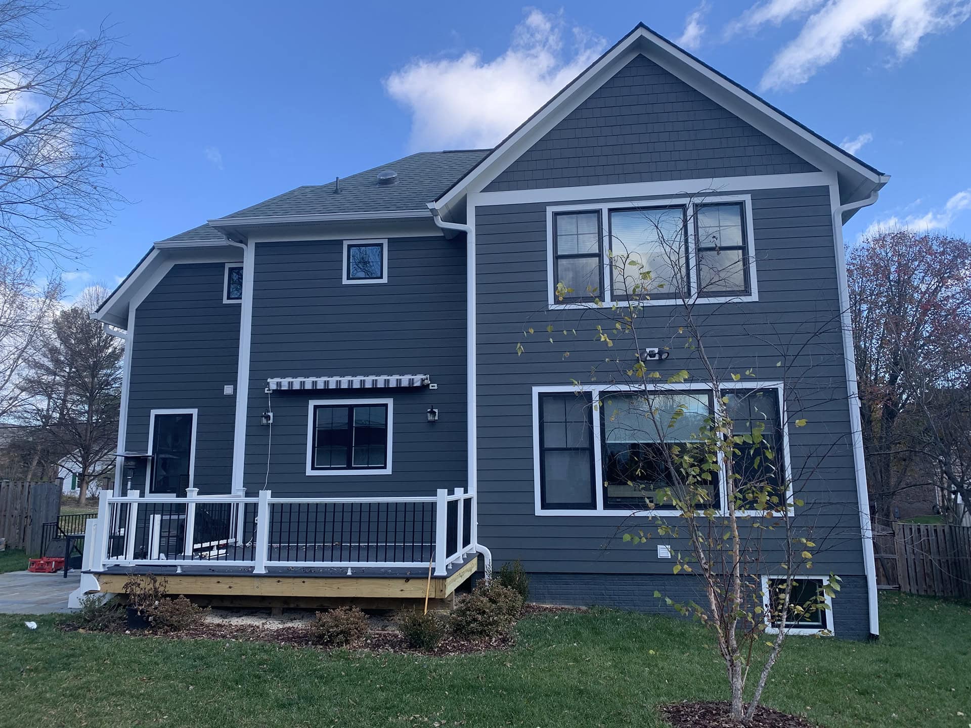 Gray house featuring a new screened-in porch with Trex decking, white PVC fascia, and charcoal fiberglass screens.