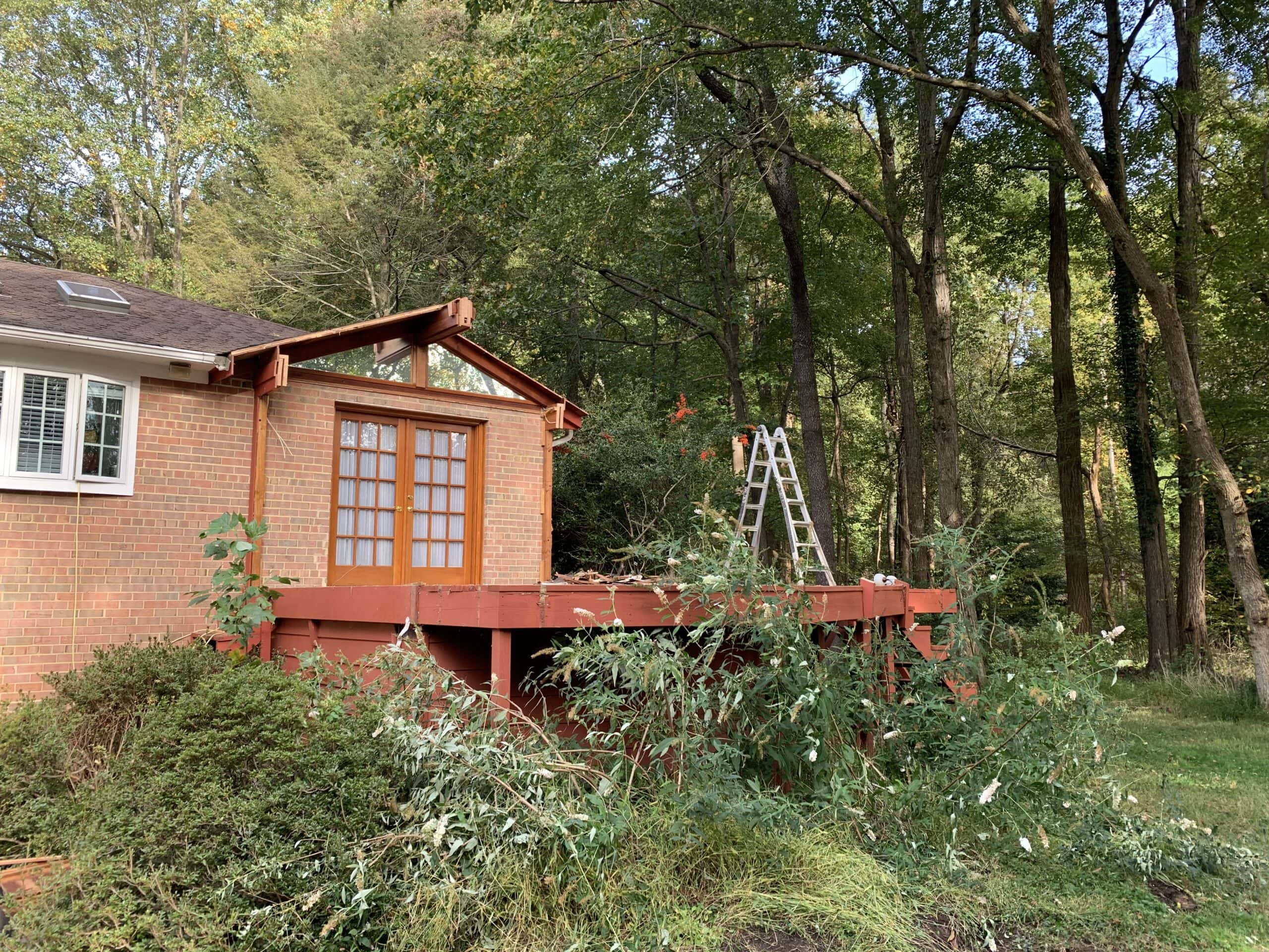 Closer view of the old addition before demolition, highlighting the dated exterior design and surrounding overgrowth