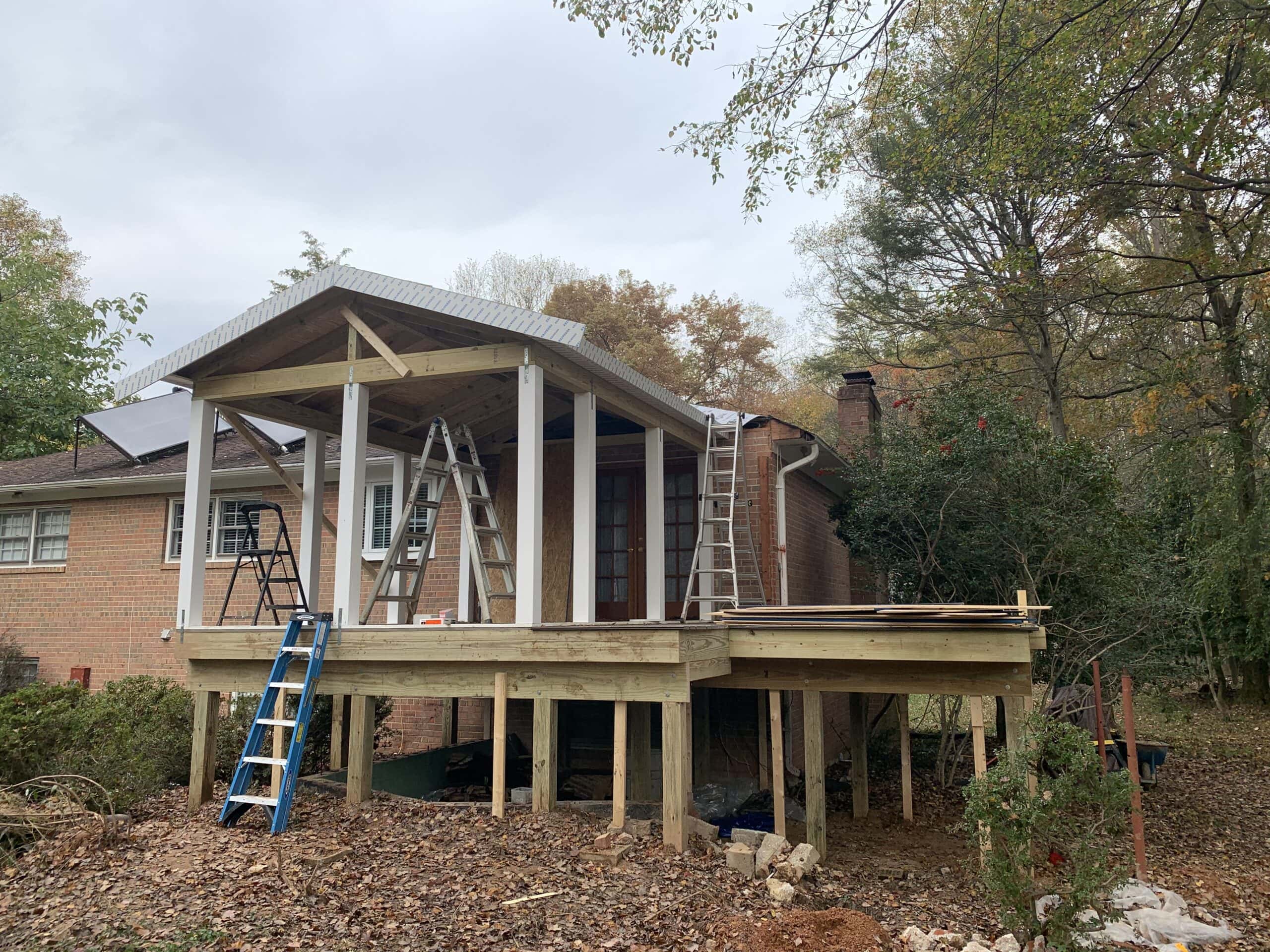 Framing of the new three-season room in progress, with the structure beginning to take shape over a fresh foundation.