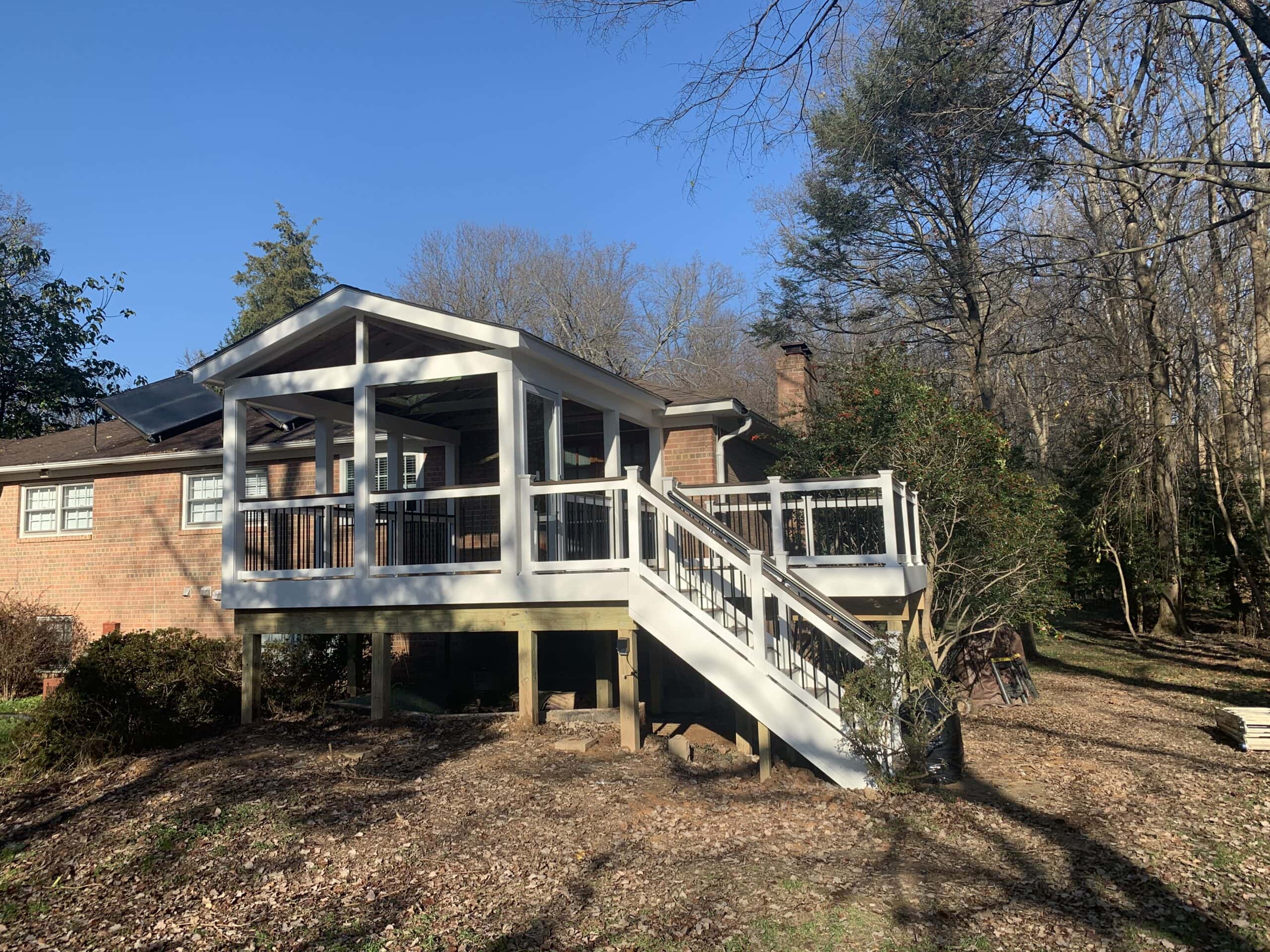 Completed exterior of the new three-season room and Trex deck with crisp white vinyl railings and black balusters for contrast.