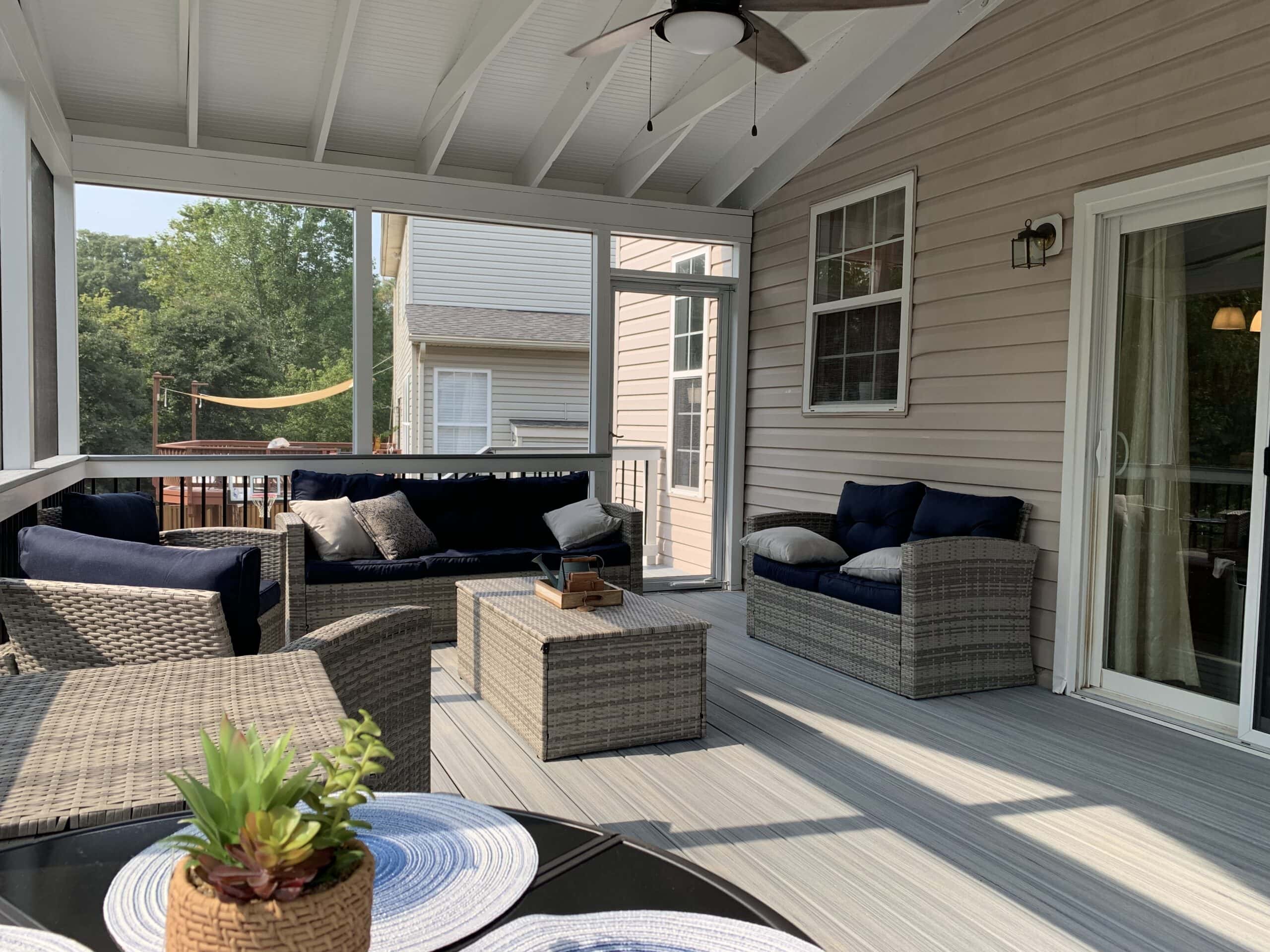 A screened porch with wicker furniture and a ceiling fan.
