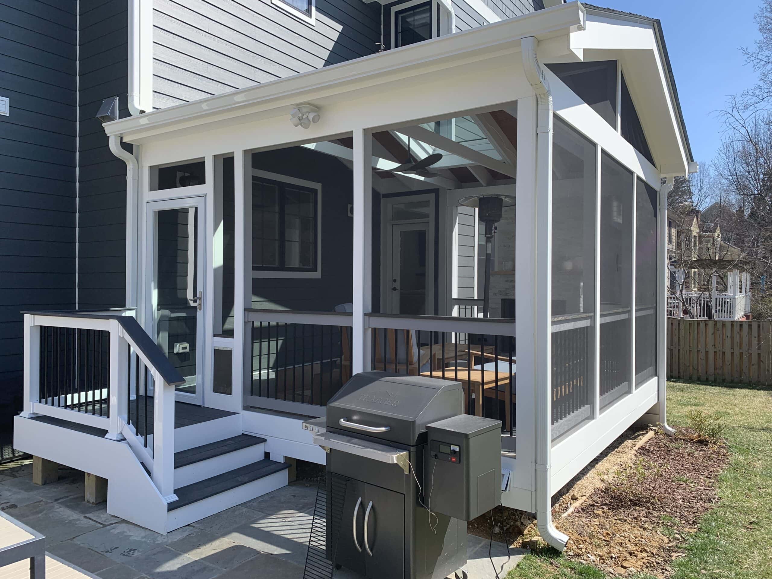 A gray house featuring a new screened-in porch with Trex decking, charcoal fiberglass screens, and a cozy gas fireplace